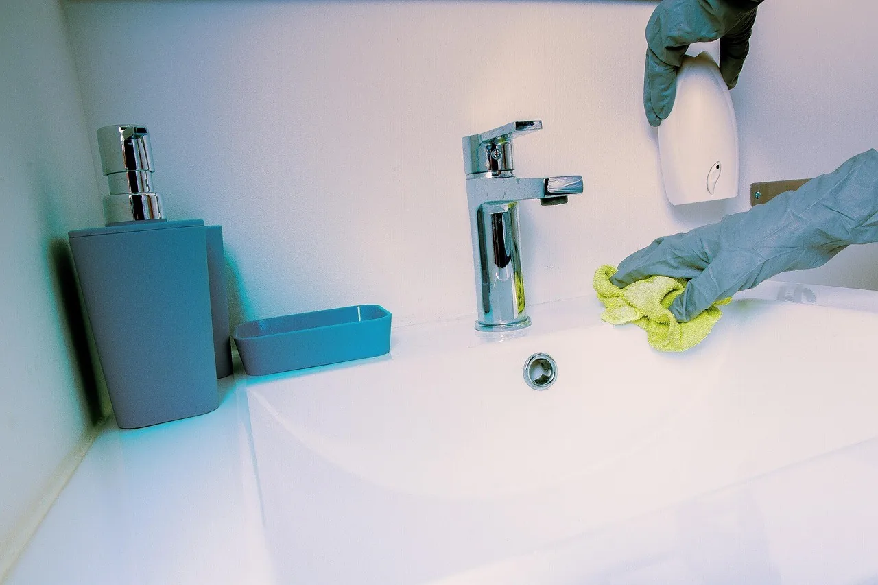 A gloved hand wiping a bathroom basin