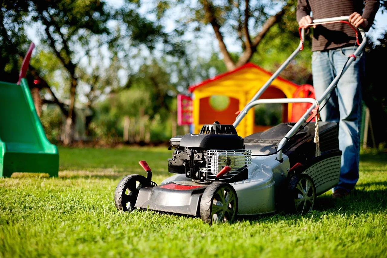 Someone pushing a lawn mower across a green lawn